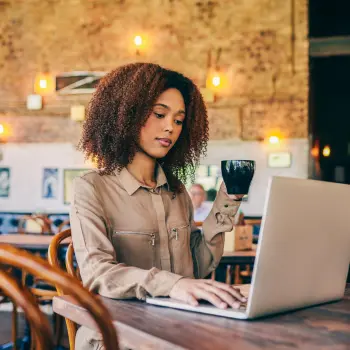 Lady drinking coffee whilst using laptop in coffee shop